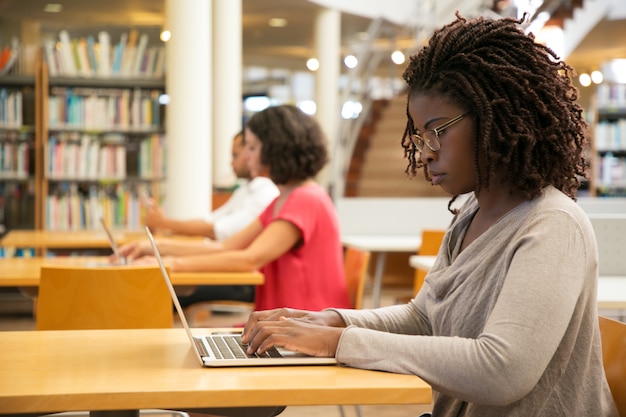 Cliente femminile concentrato che utilizza hotspot Wi-Fi pubblico nella biblioteca