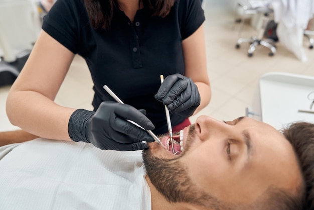 Cliente sdraiato con la bocca aperta mentre il medico cura i denti