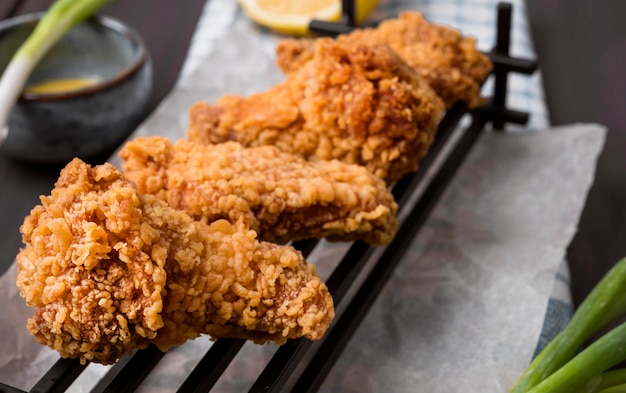 Close-up di ali di pollo fritte sul vassoio con cipolle verdi