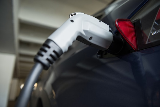 Close-up di auto in carica con caricabatteria per auto elettriche