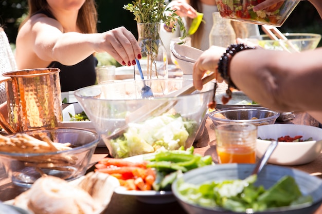 Close-up di ciotole e piatti con cibo e mano femminile con forchetta