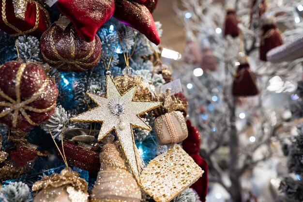 Close up di diversi oggetti giocattolo regali appesi a un albero di Natale decorato.