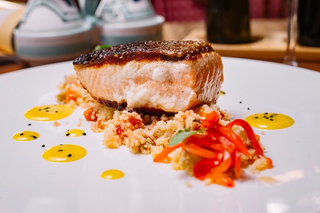 Close up di filetto di pesce alla griglia servito in cima l'insalata di couscous con peperoni