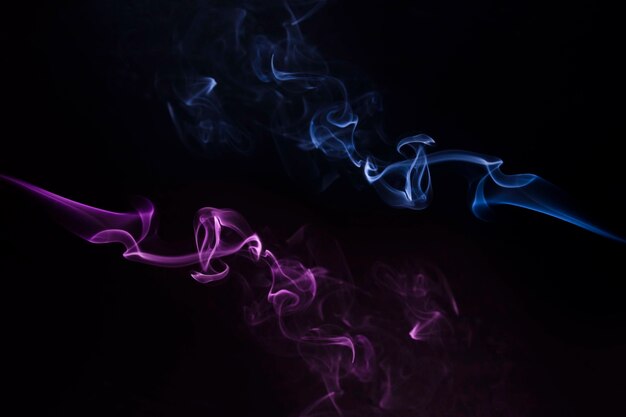 Close-up di fumo blu e viola vorticoso su sfondo nero