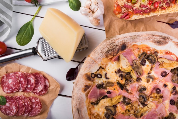 Close-up di funghi pepperoni pizza con formaggio blocco; grattugia e ingredienti