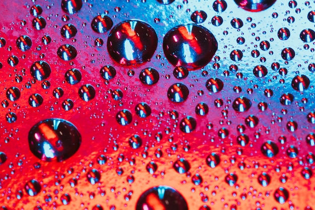 Close-up di gocce d&#39;acqua e goccioline sulla superficie luminosa