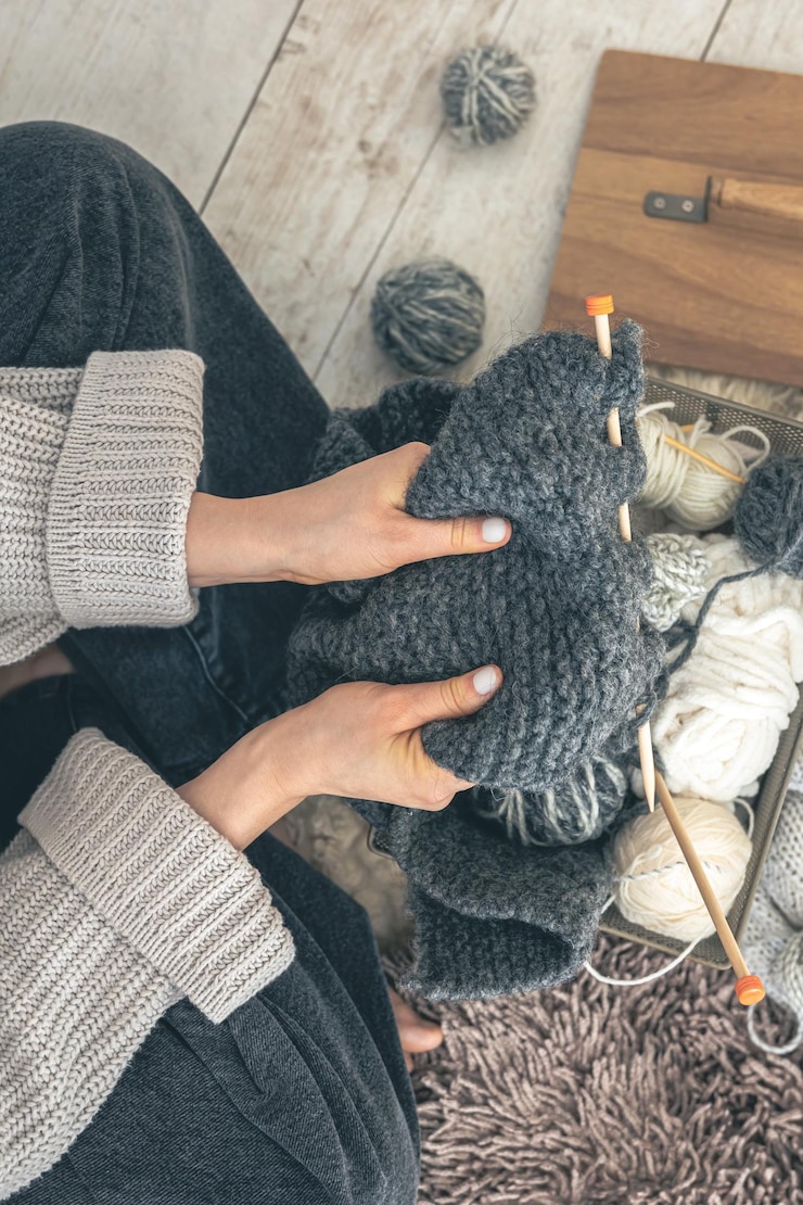 Foto gratuito close-up di mani femminili che magliano un maglione di lana grigia vista superiore