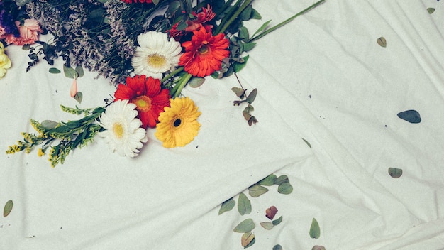 Close-up di solidago gigantea e fiori colorati gerbera sul panno bianco
