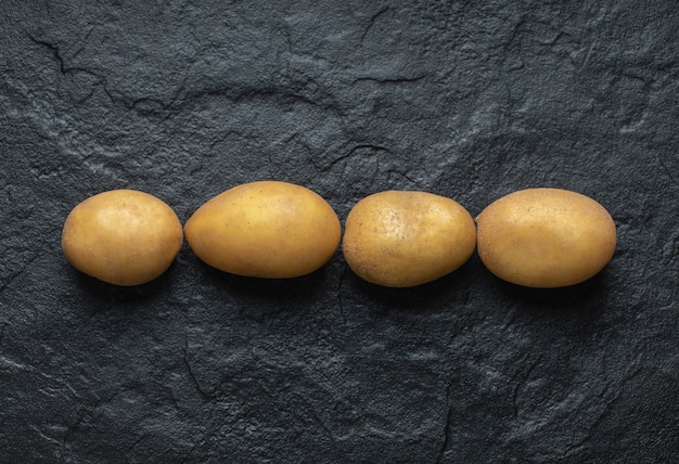 Close up foto del mucchio di patate fresche biologiche su sfondo nero.