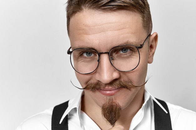 Close up foto di attraente banchiere positivo con baffi a manubrio, barba pizzetto e occhi azzurri intelligenti