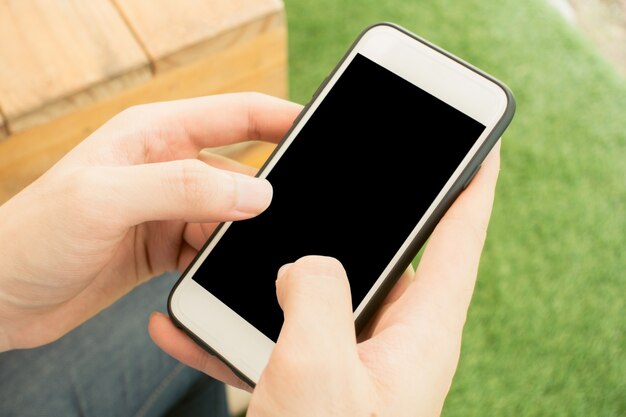 Close-up mano toccare sul telefono cellulare bianco vuoto schermo concetto di stile di vita all&#39;aperto sullo sfondo sfocato della natura - può essere utilizzato immagine imbrattata. Immagini di stile d&#39;effetto vintage.