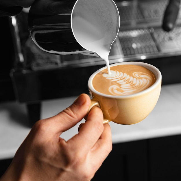 Close-up mano versando il latte nella tazza di caffè