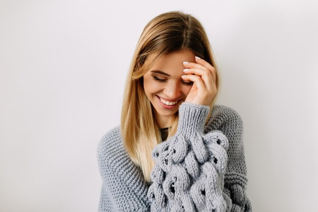 Close up ritratto di donna affascinante con capelli biondi che copre il viso e sorridente con gli occhi chiusi