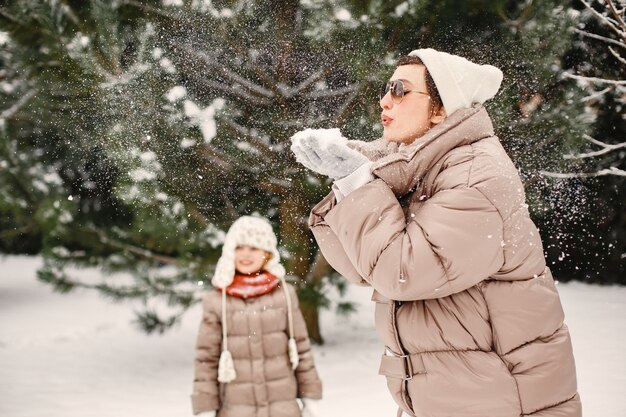 Close-up ritratto di donna in giacca marrone nel parco innevato con sua figlia