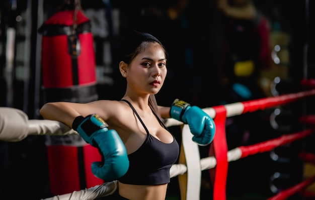 Close up ritratto giovane bella donna in guantoni da boxe in piedi su tela dopo l'allenamento con stanco, allenamento in palestra per il fitness,