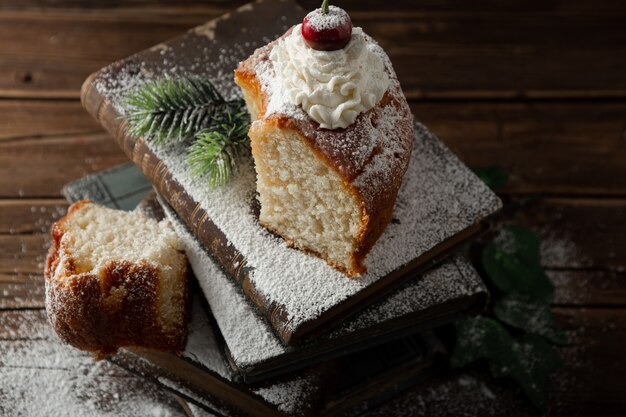 Closeup colpo di delizioso dessert con panna, zucchero a velo e una ciliegina sulla torta sui libri