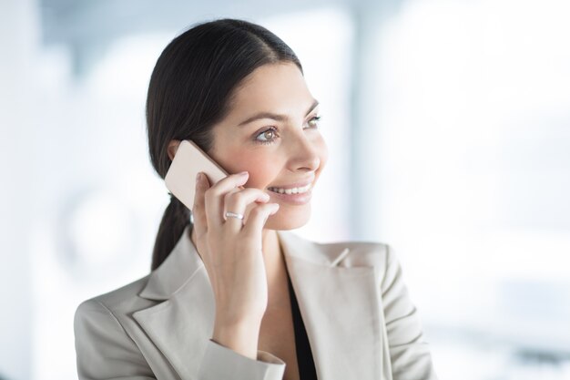Closeup della donna sorridente di affari che comunica sul telefono