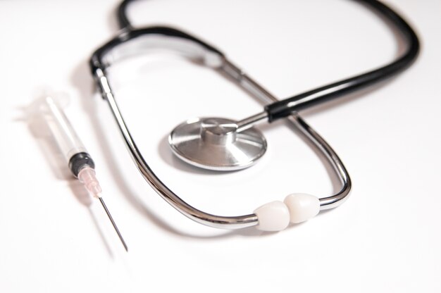 Closeup di medicinali, siringhe e stetoscopio. Immagine pulita e luminosa. Siringa di plastica con ago isolata su sfondo bianco