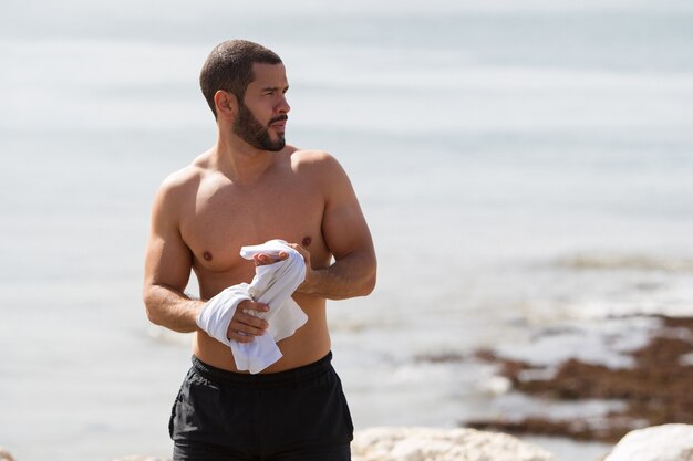 Closeup di uomo forzato senza camicia che si distende sul mare