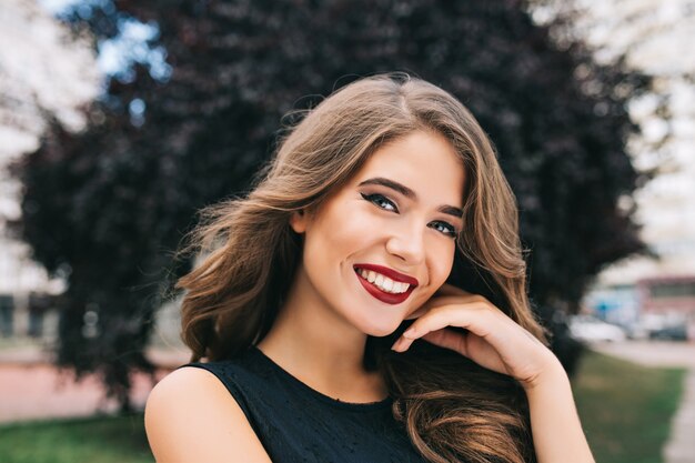 Closeup ritratto di bella ragazza con lunghi capelli ricci sulla strada