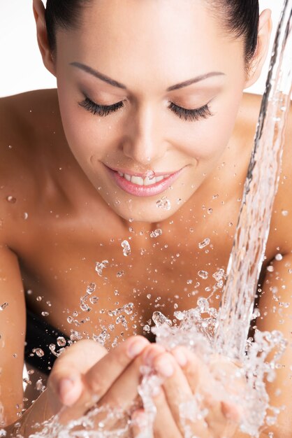 Closeup ritratto di una donna sorridente che lava il viso pulito con acqua