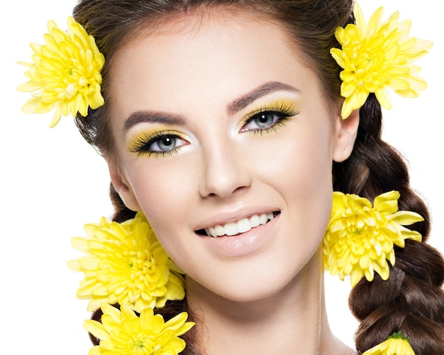 Closeup volto di una giovane bella donna sorridente con trucco giallo brillante Moda ritratto Ragazza attraente con trecce acconciatura alla moda isolata on white Trucco professionale