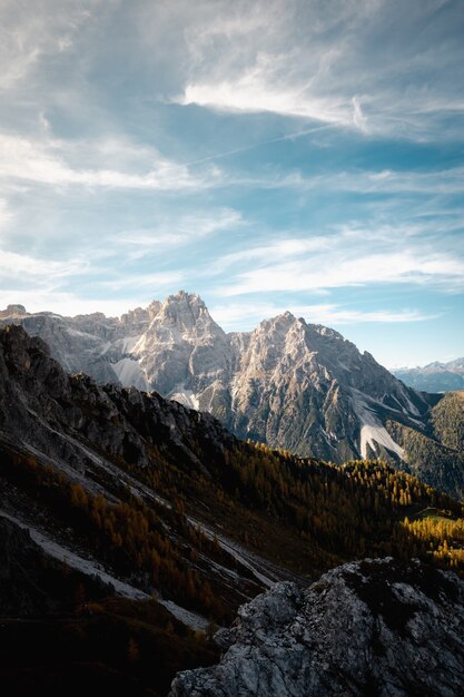 Cloudscape maestoso sulla catena montuosa delle Dolomiti ricoperte di erba rocciosa in Italia con macchie di neve