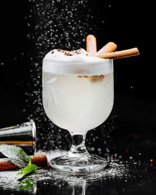 Cocktail al latte di cocco con schiuma e bastoncini di cannella.