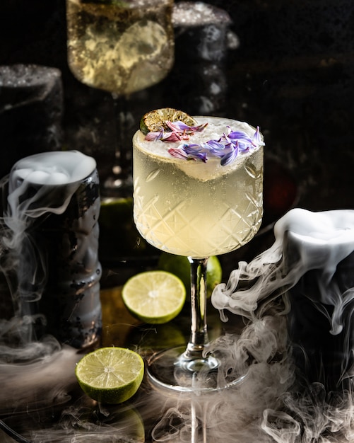Cocktail al lime decorato con calce e petali di fiori in vetro a gambo lungo