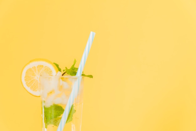 Cocktail al limone con cannuccia di plastica su sfondo giallo