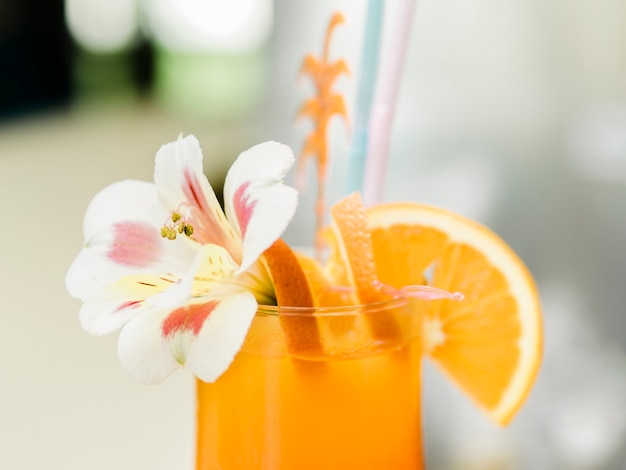 Cocktail arancione con frutta decorata con orchidea