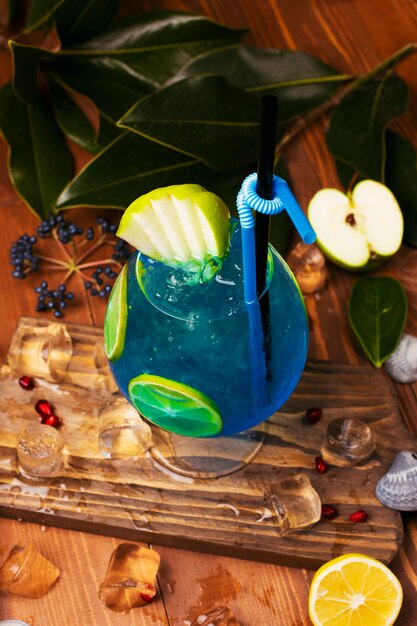 Cocktail blu della laguna con le fette del limone in vetro sulla tavola di legno