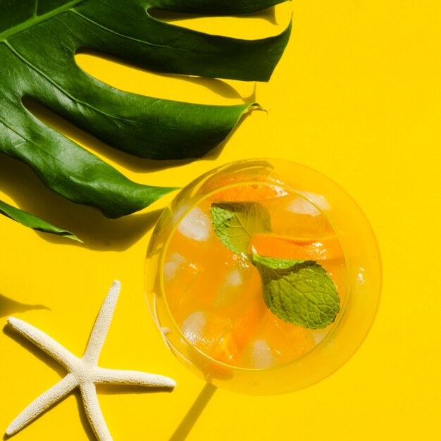 Cocktail con arancia, menta e ghiaccio vicino stella di mare