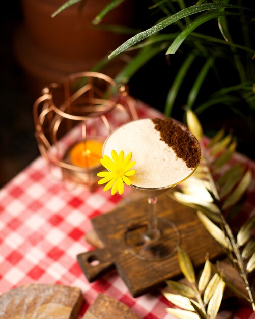 Cocktail con schiuma e cacao in polvere decorato con fiori