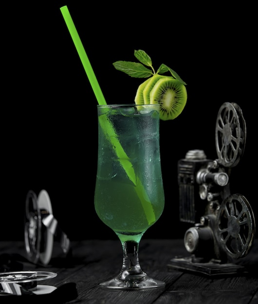 Cocktail dell'alcool del kiwi con le fette della frutta e il tubo verde.