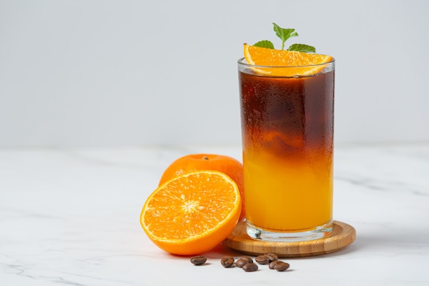 Cocktail di arancia e caffè sulla superficie bianca.