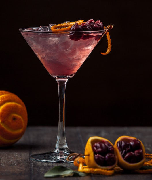 Cocktail di ciliegie guarnito con scorza e ghiaccio di ciliegia e arancia