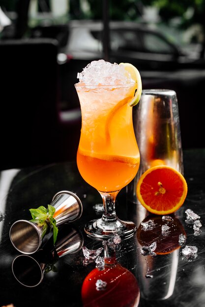 Cocktail di pompelmo fresco con cubetti di ghiaccio e fette di frutta in un bicchiere.