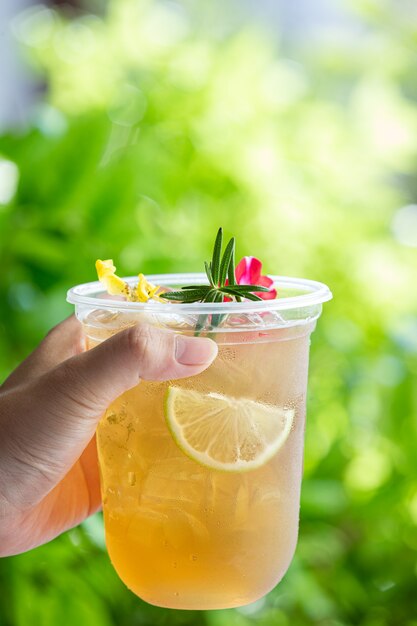 Cocktail di tè freddo alle erbe con fiori commestibili su una superficie di legno