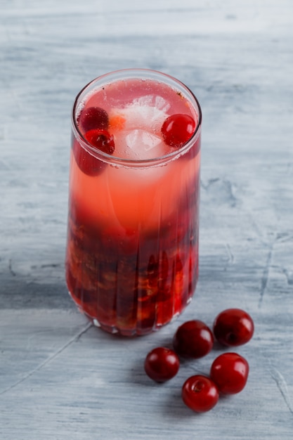 Cocktail ghiacciato di ciliegia in una brocca con ciliegie alte