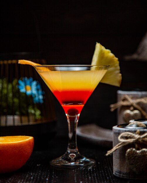 Cocktail giallo rosso con frutta e arancia dell'ananas.