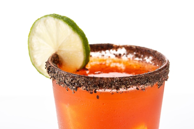 Cocktail michelada fatto in casa con succo di lime e birra con salsa calda Rim e succo di pomodoro isolati