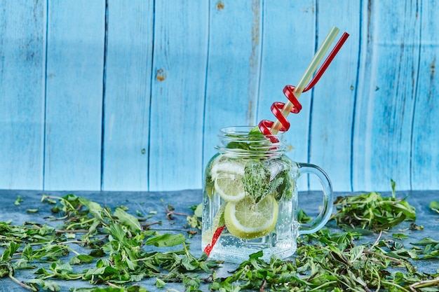 Cocktail Mojito con fette di lime e menta sul tavolo blu con foglie di menta fresca