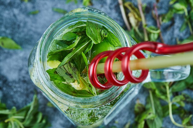 Cocktail Mojito con fette di lime e menta sul tavolo blu con foglie di menta fresca