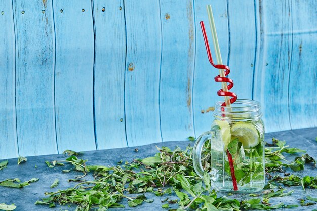 Cocktail Mojito con fette di lime e menta sul tavolo blu con foglie di menta fresca