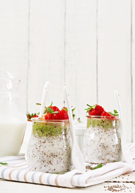 Colazione disintossicante e salutare da supercibi in barattolo. Budino vegano dei semi di chia del latte di cocco con le fragole ed il kiwi.