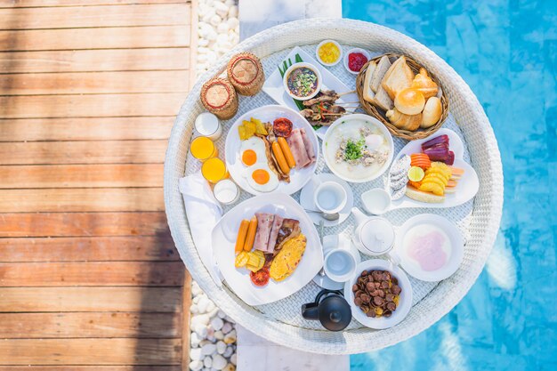 Colazione galleggiante impostata nel vassoio con frittata di uova fritte salsiccia pane pane frutta latte succo di caffè