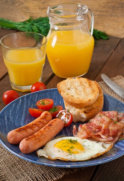 Colazione inglese - toast, uova, pancetta e verdure in stile rustico sul tavolo di legno