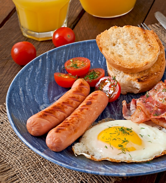 Colazione inglese - toast, uova, pancetta e verdure in stile rustico sul tavolo di legno