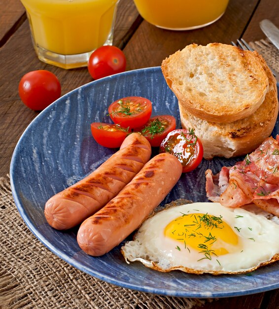 Colazione inglese - toast, uova, pancetta e verdure in stile rustico sul tavolo di legno